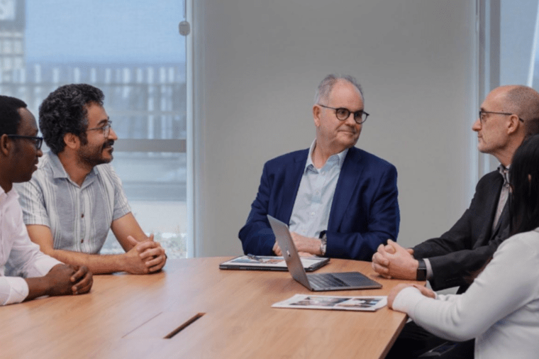 Five people in discussion around a table.