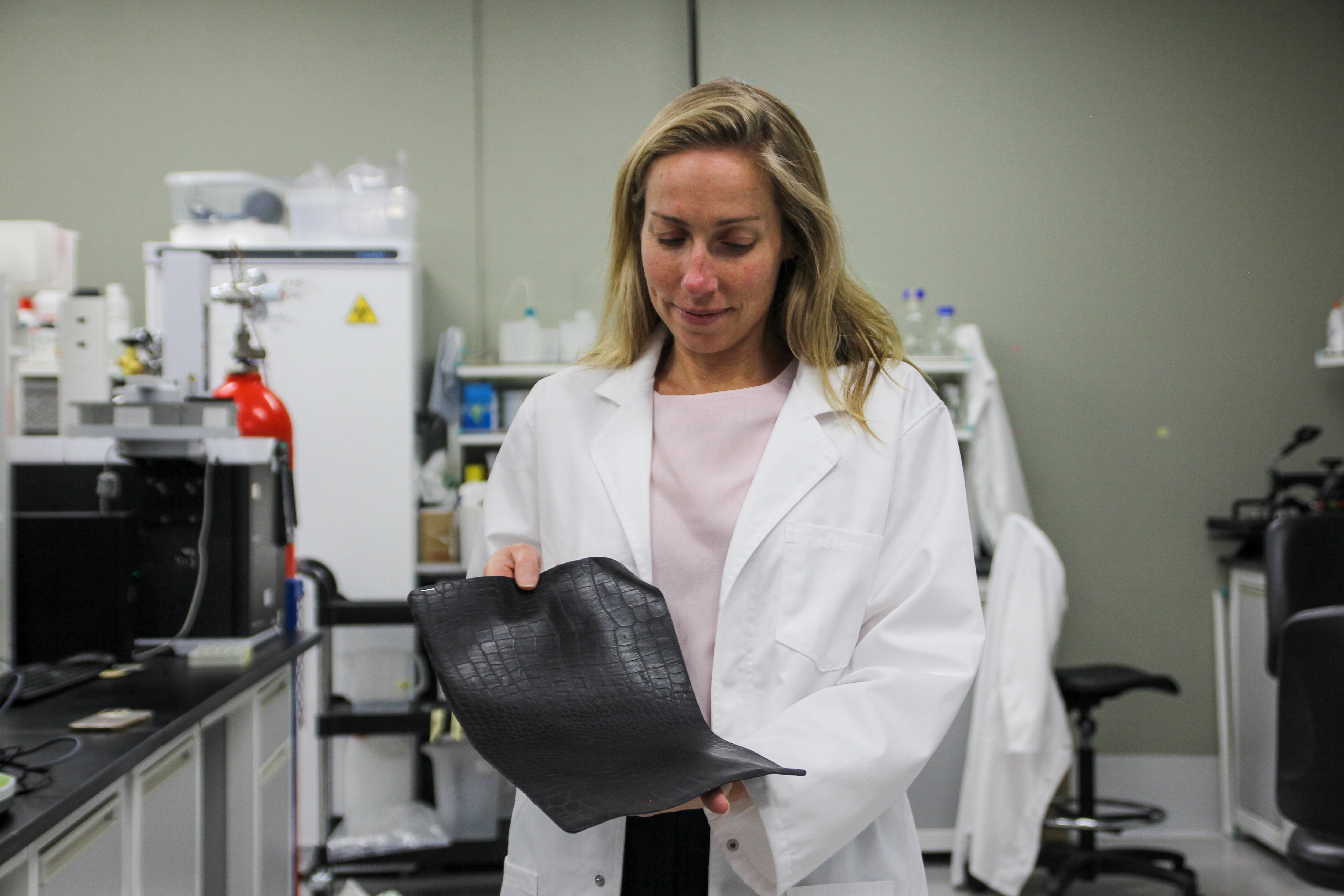 Image of Tina Lunder in the Alt. Leather lab holding a piece of their leather alternative.