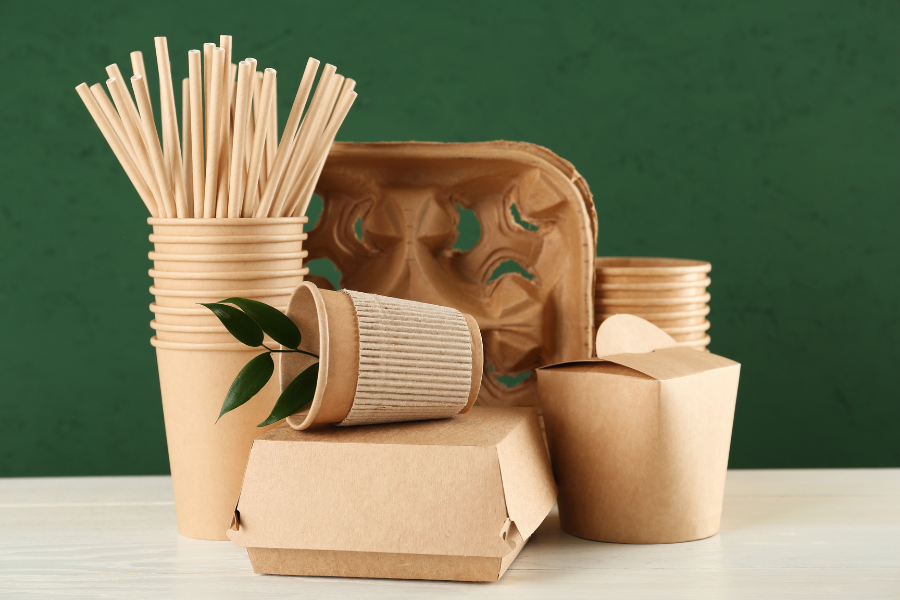 Paper cups and plates with green leaves growing out of them.