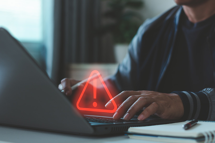 Man using a laptop with a red exclamation mark overlaid on the image