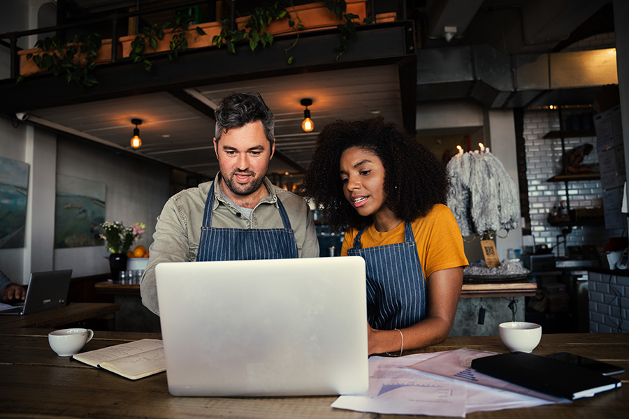 Two cafe workers using a laptop together