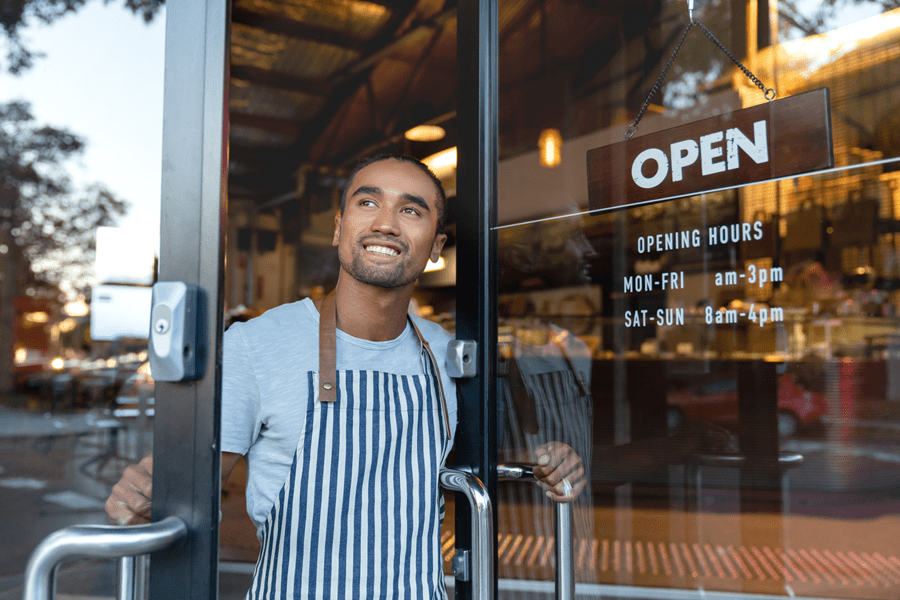 Smiling man opening a cafe door