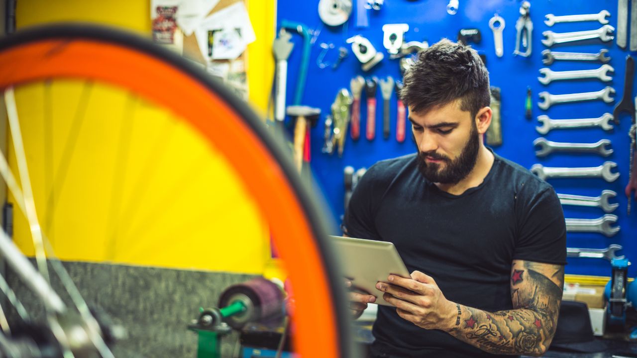 Man in a bike shop looking at a tablet.